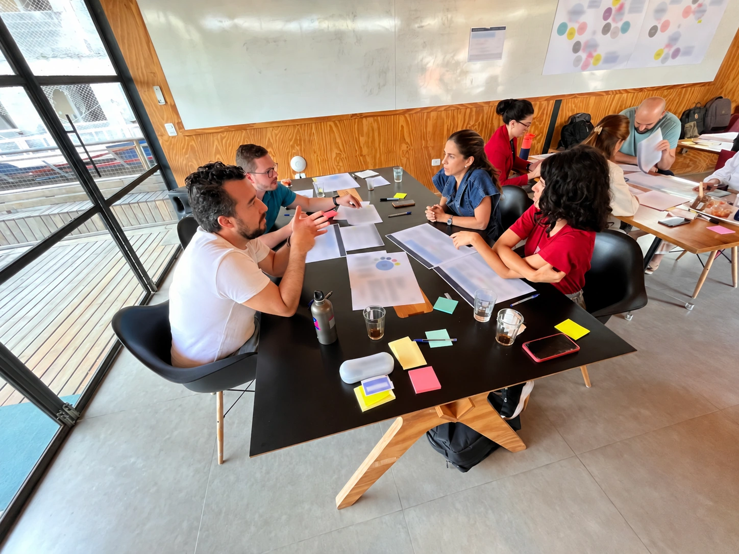 Equipe Kraft Heinz em workshop à mesa, com documentos estratégicos protegidos
